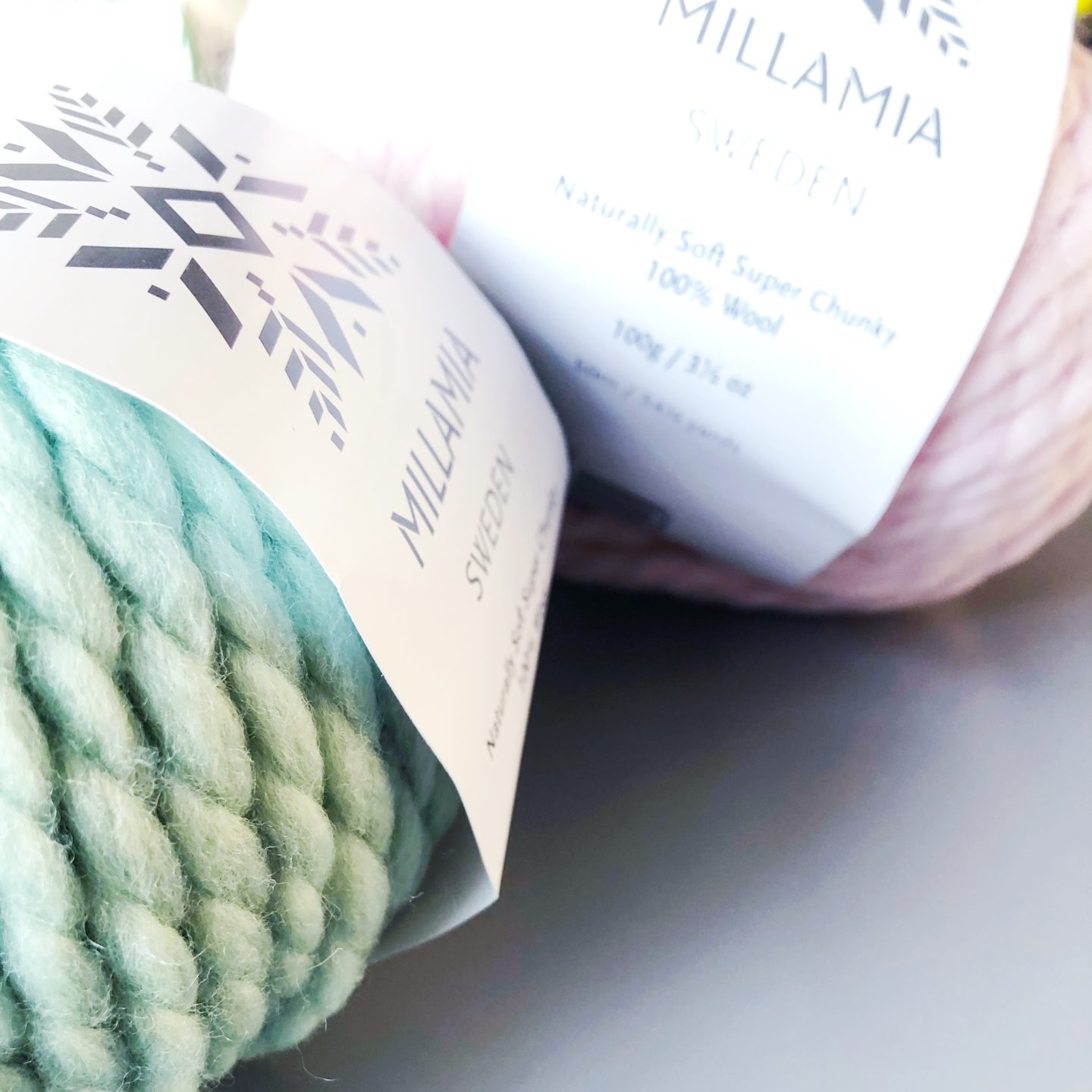 A close up picture of mint green and pale pink Millmia balls of wool