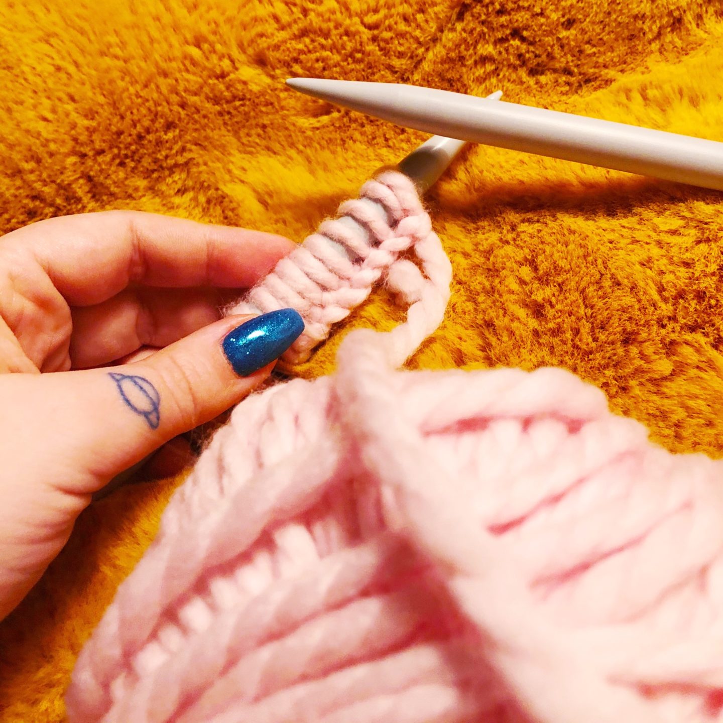 close up of Millamia pink yarn on the knitting needle.